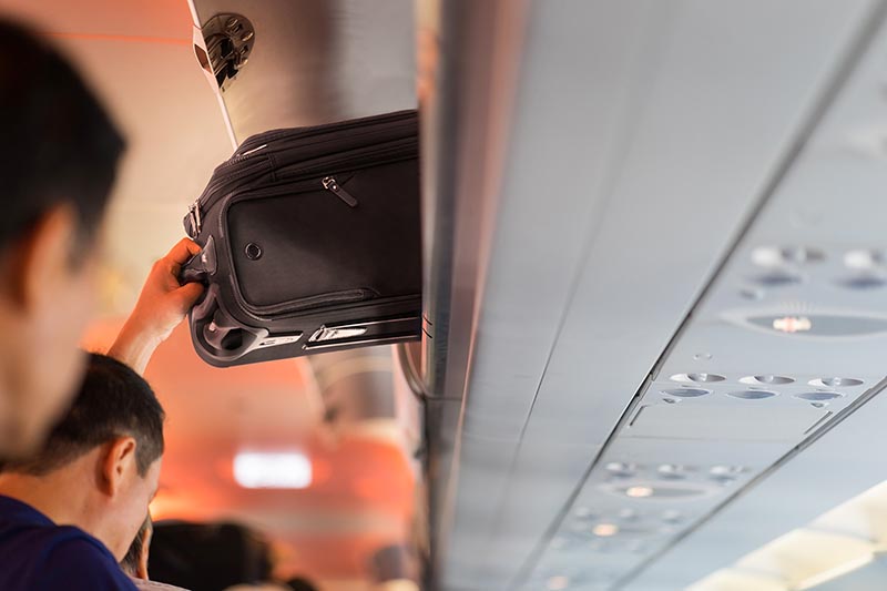 carry-on luggage being placed in a aircraft overhead bin